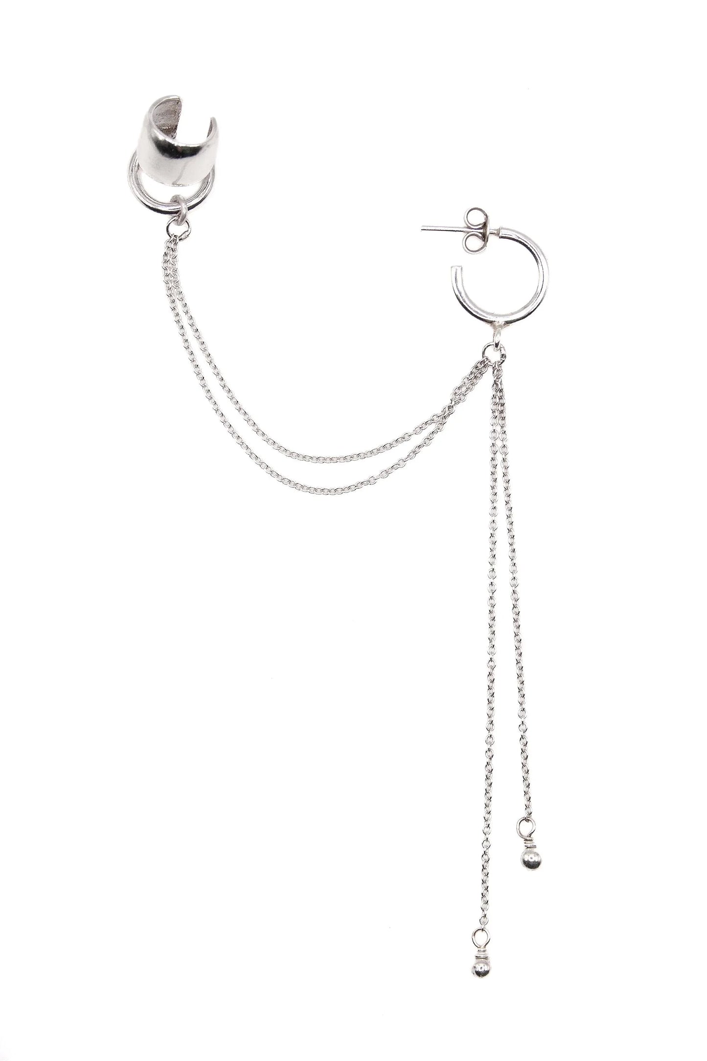 Silver ear cuff and hoop earring connected by delicate chains on white background