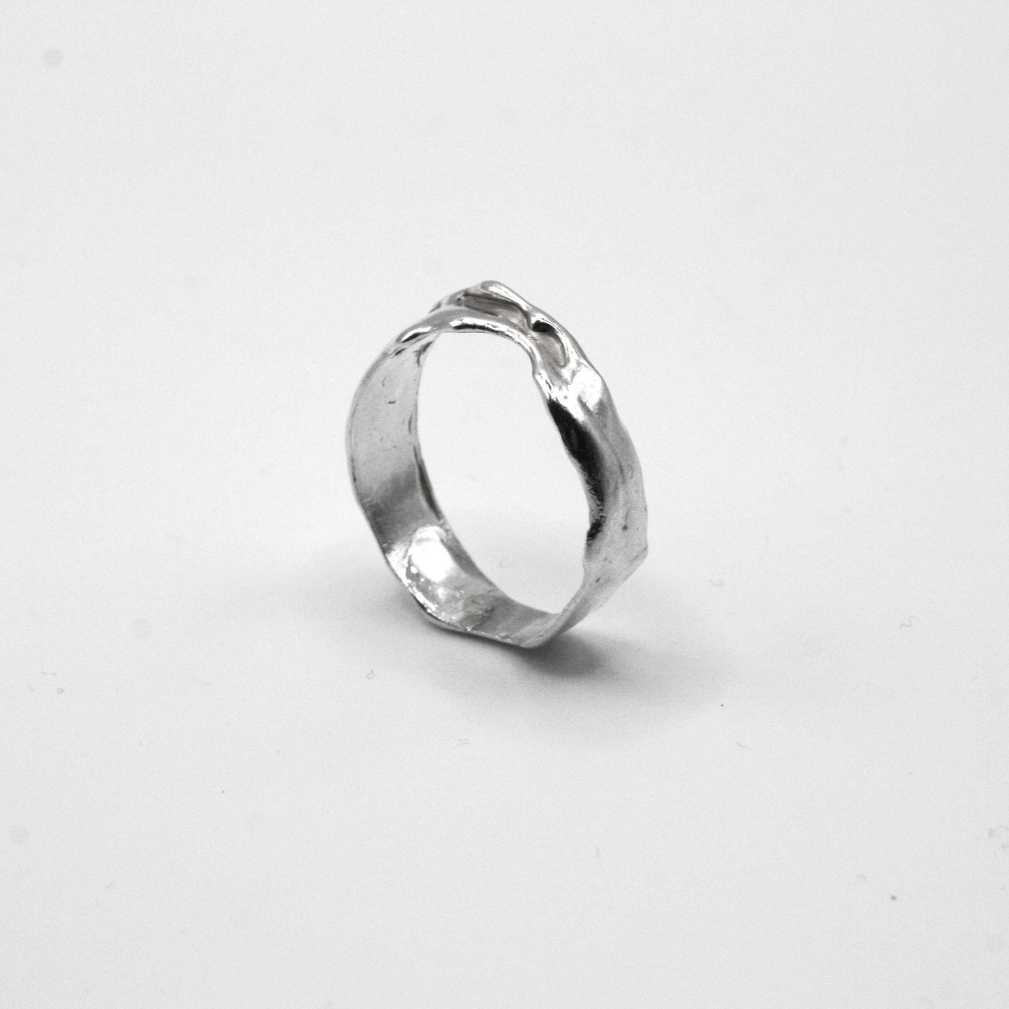 Handmade silver textured ring with organic, uneven design on white background