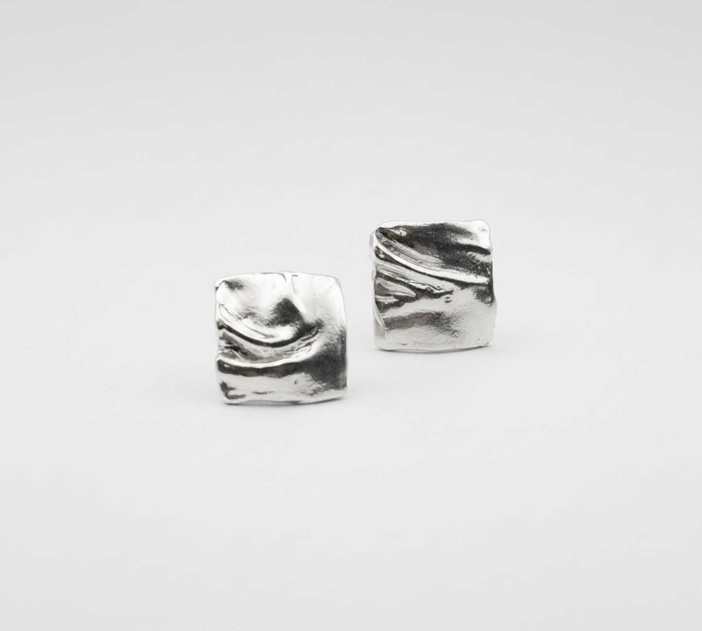 Pair of silver square earrings on a light gray background
