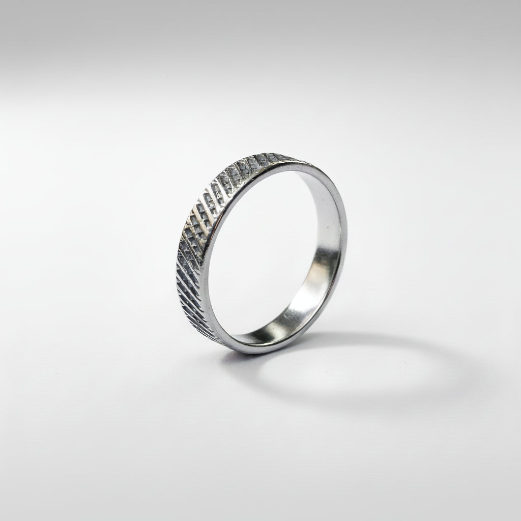 Silver ring with a textured pattern on a white background