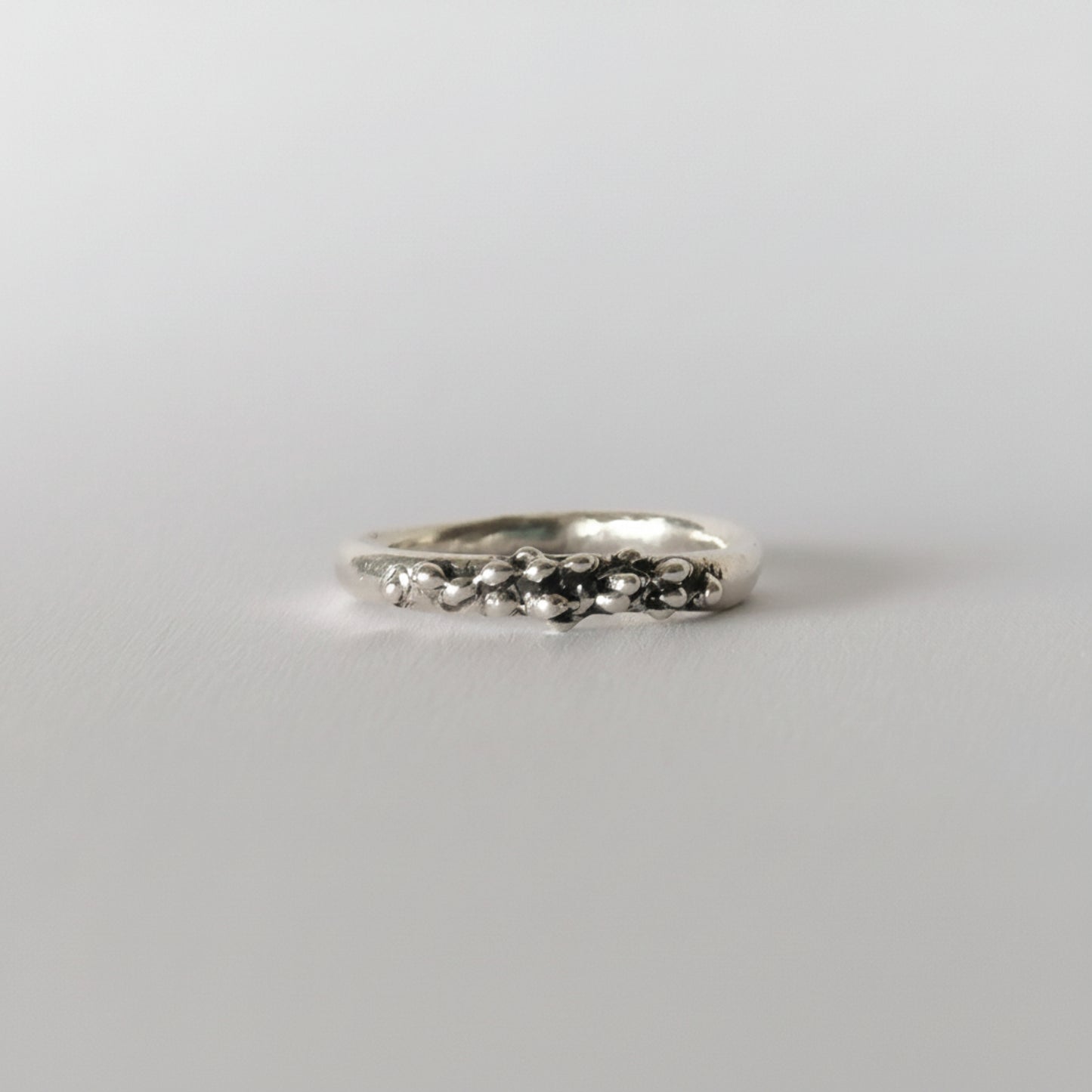 Silver ring with small stones on a light gray background