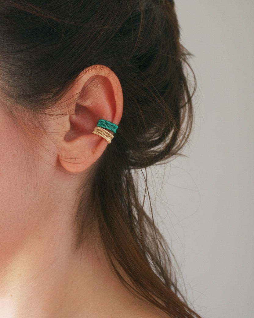 Close-up of an ear with a small green and gold earring.