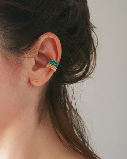 Close-up of an ear with a small green and gold earring.