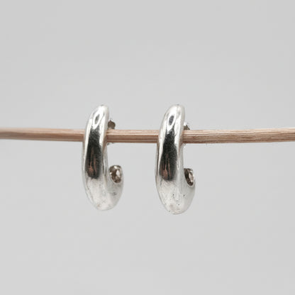 Silver hoop earrings on a thin rod against a light gray background