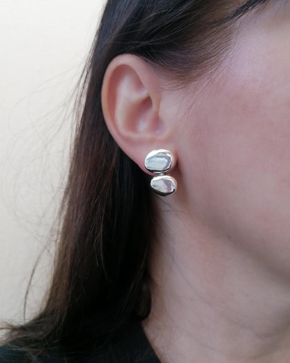 Close-up of an ear wearing silver earrings with a neutral background
