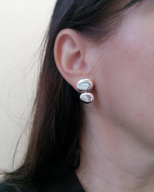 Close-up of an ear wearing silver earrings with a neutral background