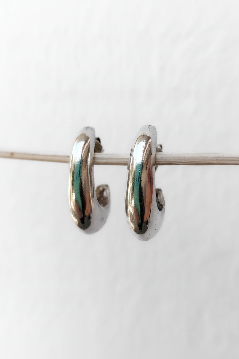 Pair of silver hoop earrings with green accents on a white background
