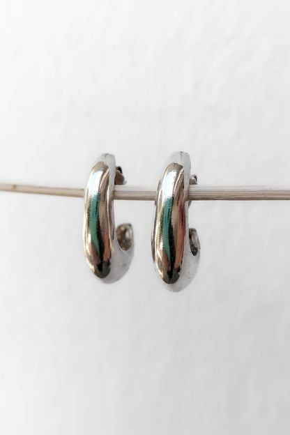 Pair of silver hoop earrings with green accents on a white background
