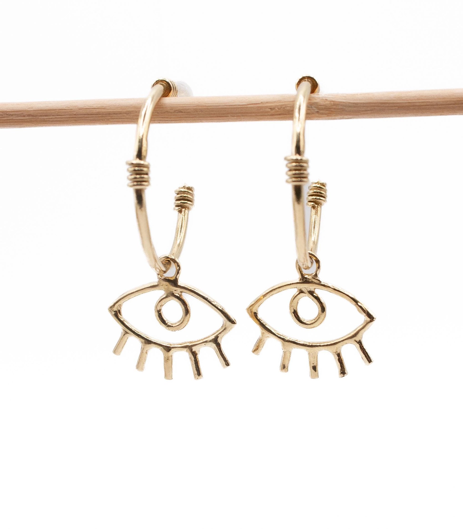 Gold hoop earrings with open eye charms, minimalist jewelry on white background