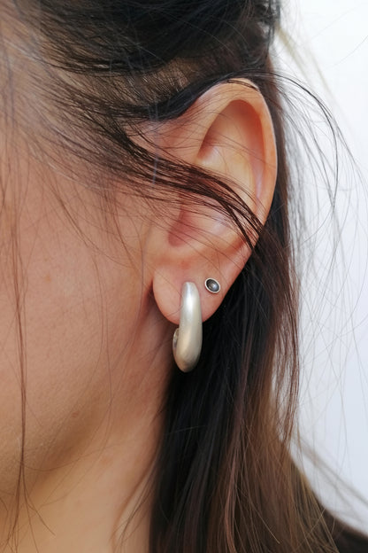 Close-up of an ear wearing a pearl earring with a plain background