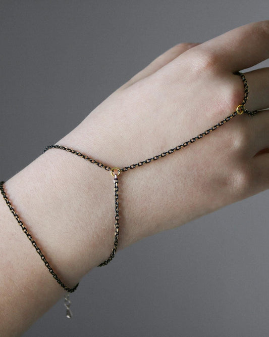 Hand wearing a delicate chain bracelet on a gray background