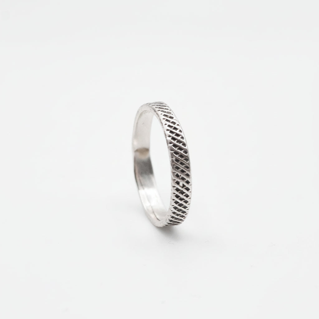 Silver ring with textured pattern on a white background