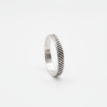 Silver ring with textured pattern on a white background