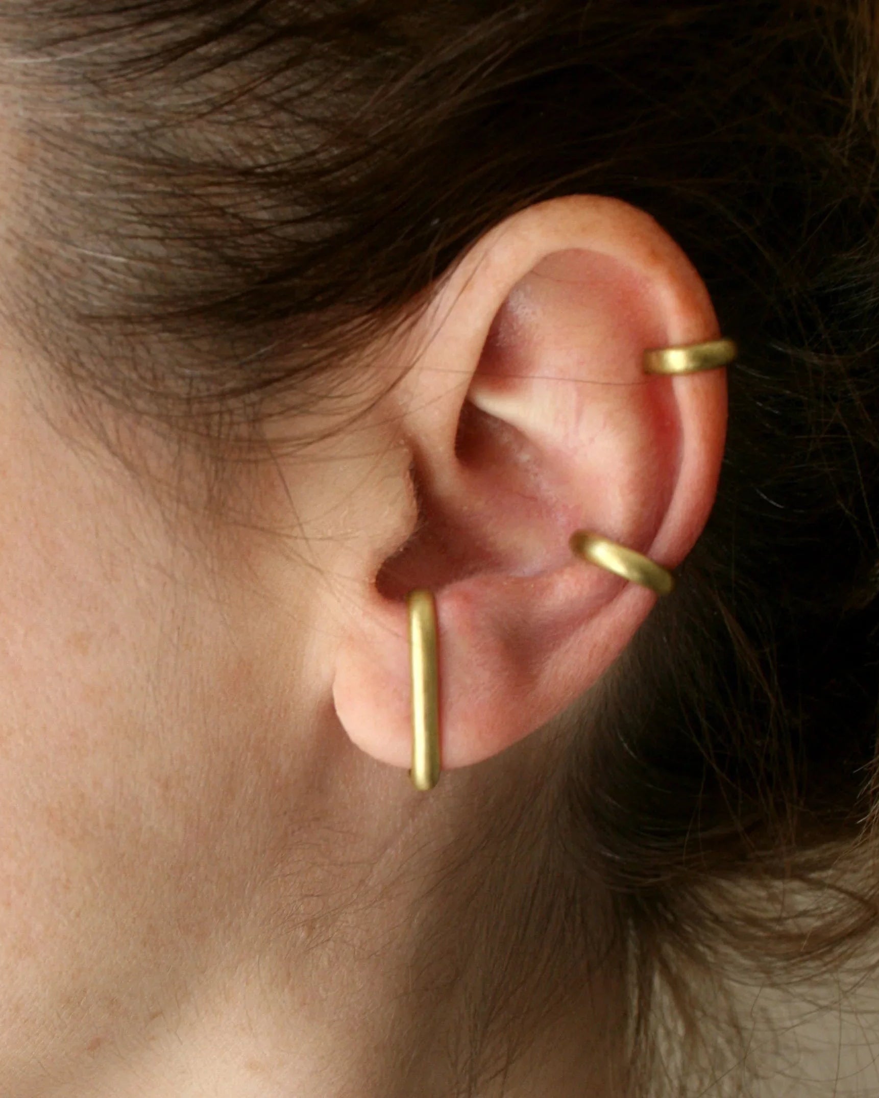 Woman wearing minimalist gold ear cuffs on cartilage and lobe