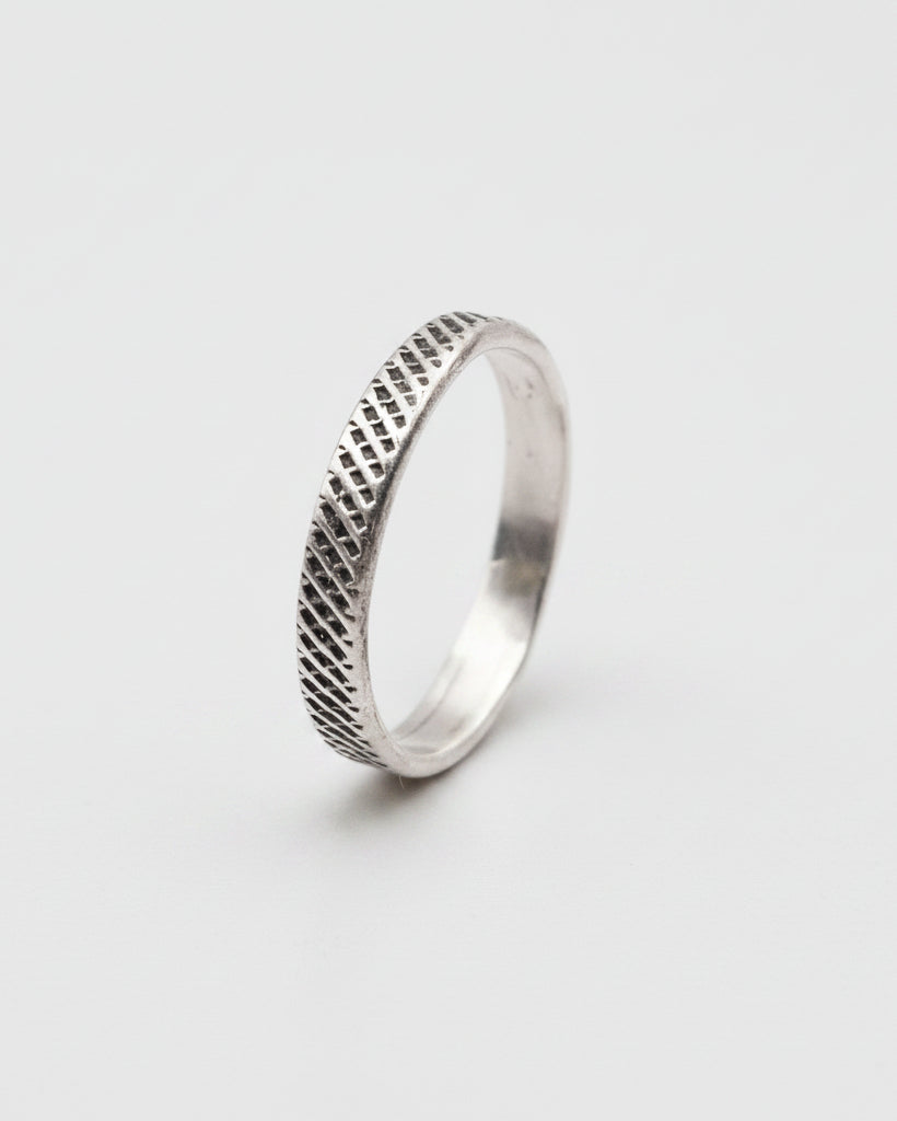 Silver ring with textured design on a white background
