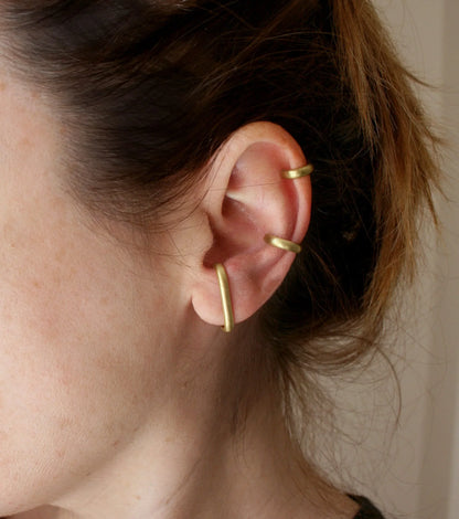 Woman wearing three minimalist gold ear cuffs on cartilage and lobe