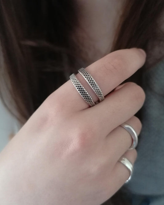 Close-up of a hand wearing two silver rings with a blurred background