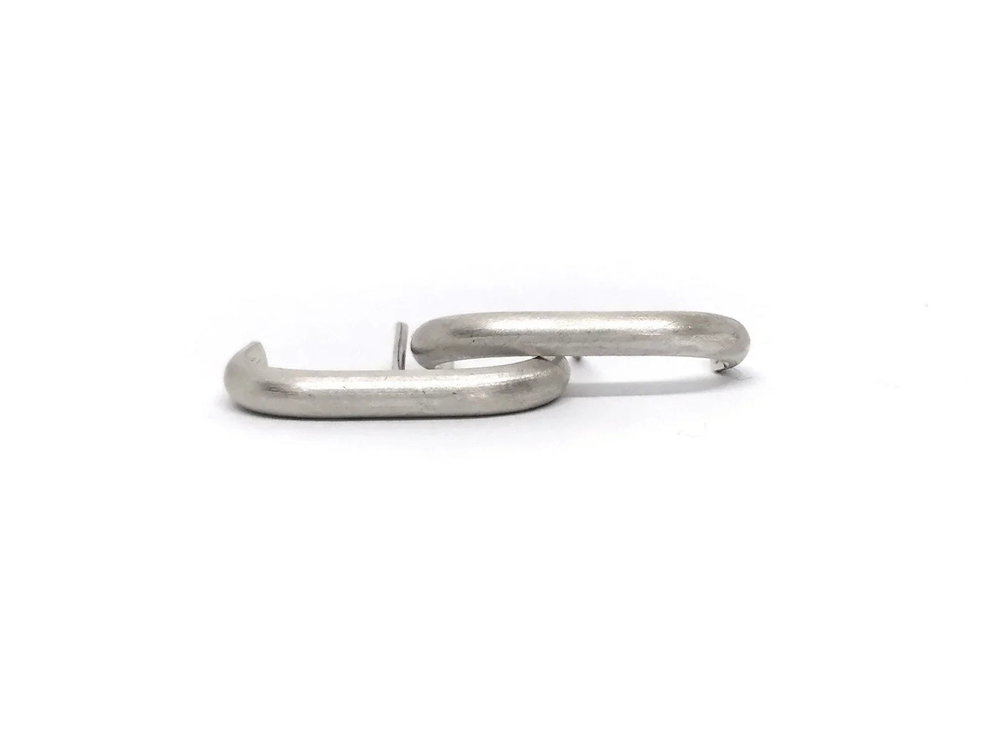 Pair of minimalist silver rectangular hoop earrings on white background