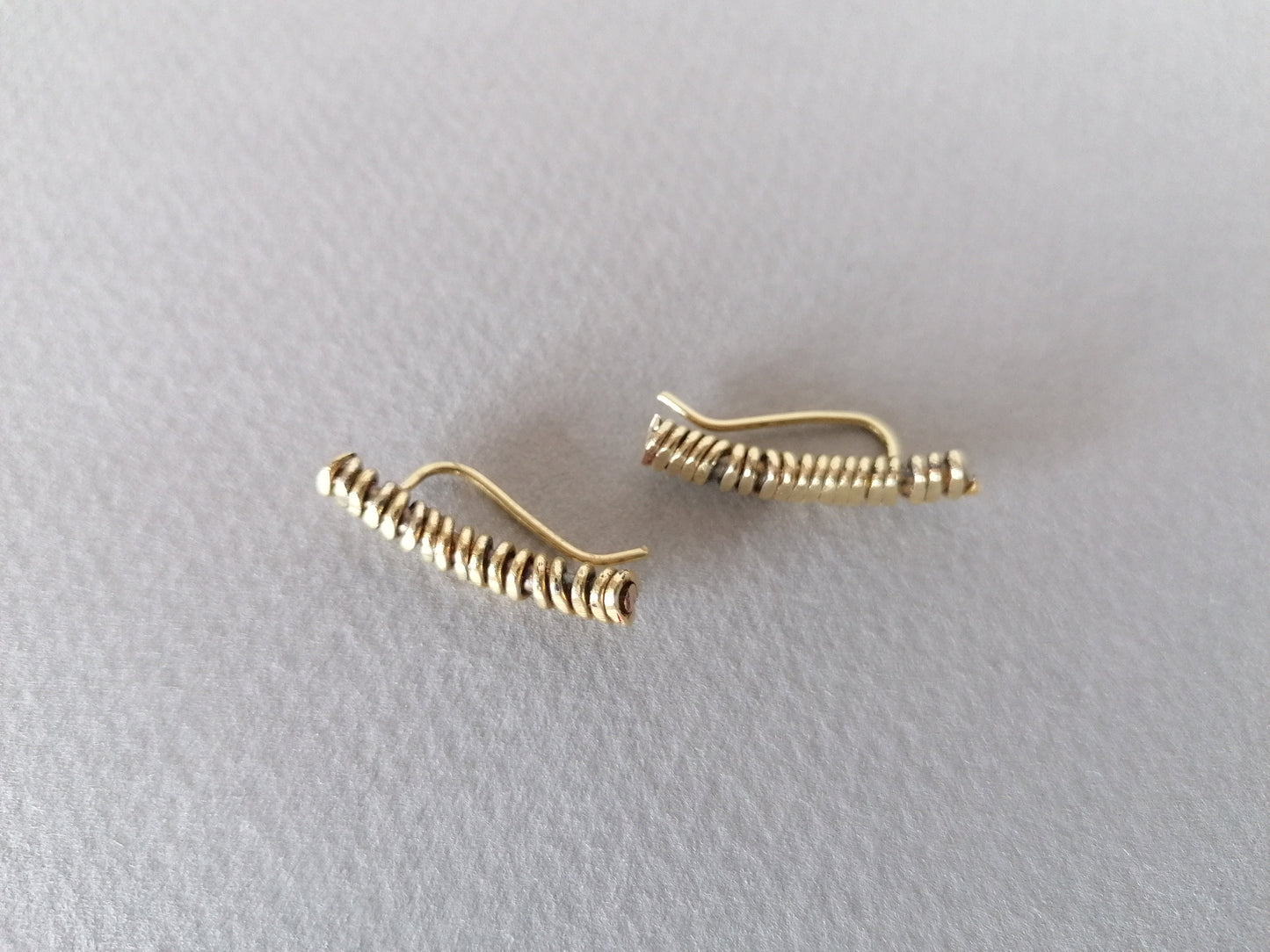 Pair of gold spiral earrings on a light gray background