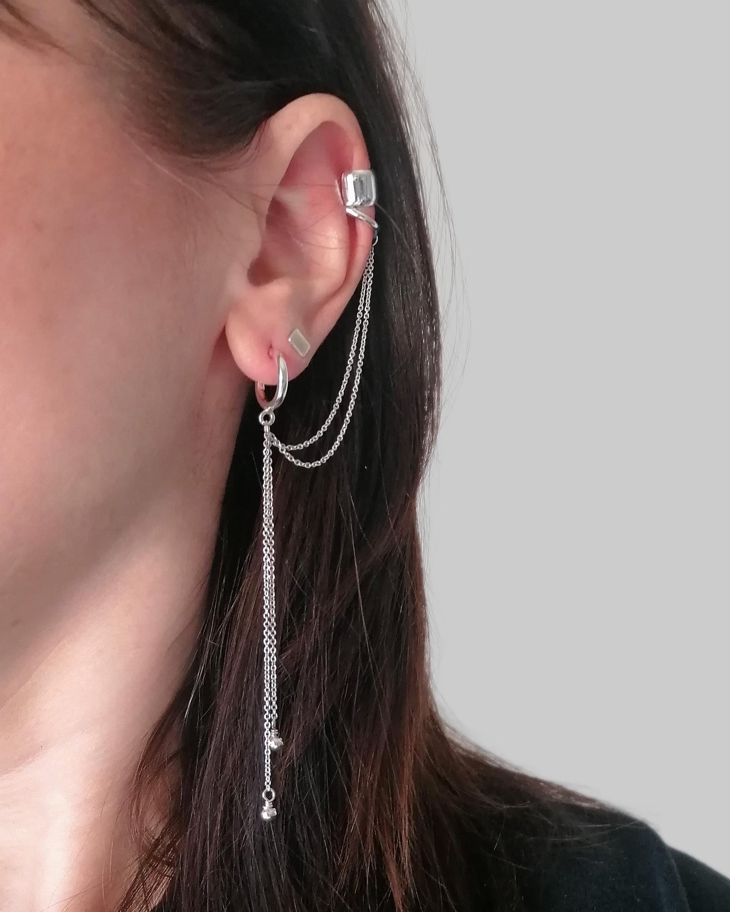 Close-up of a person wearing silver earrings with a blurred background