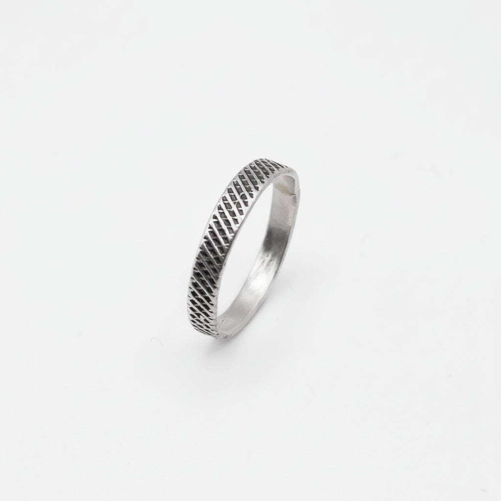 Silver ring with textured design on a white background