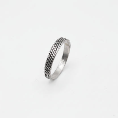 Silver ring with textured design on a white background