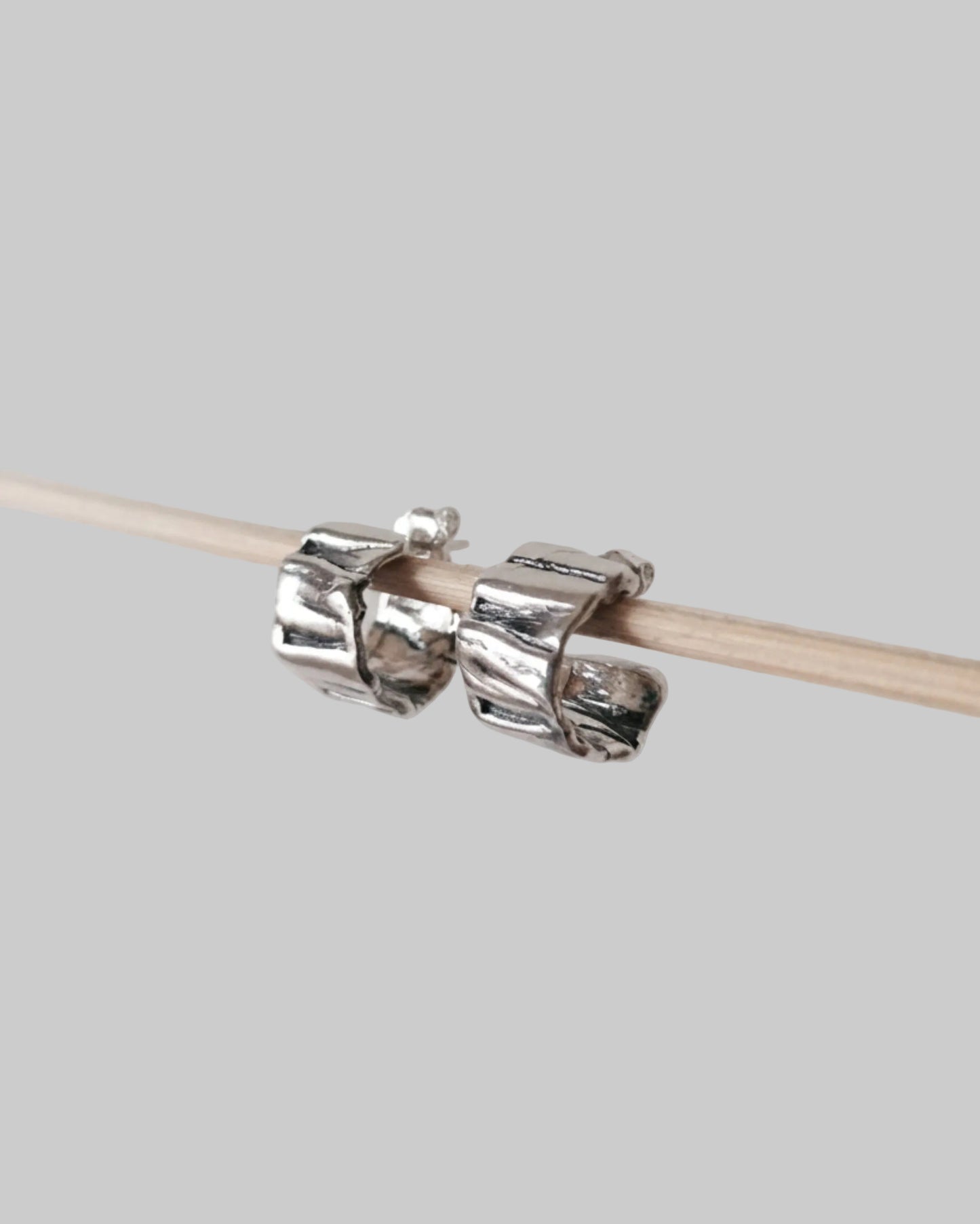 Silver knitting needle holder on a wooden knitting needle against a light gray background