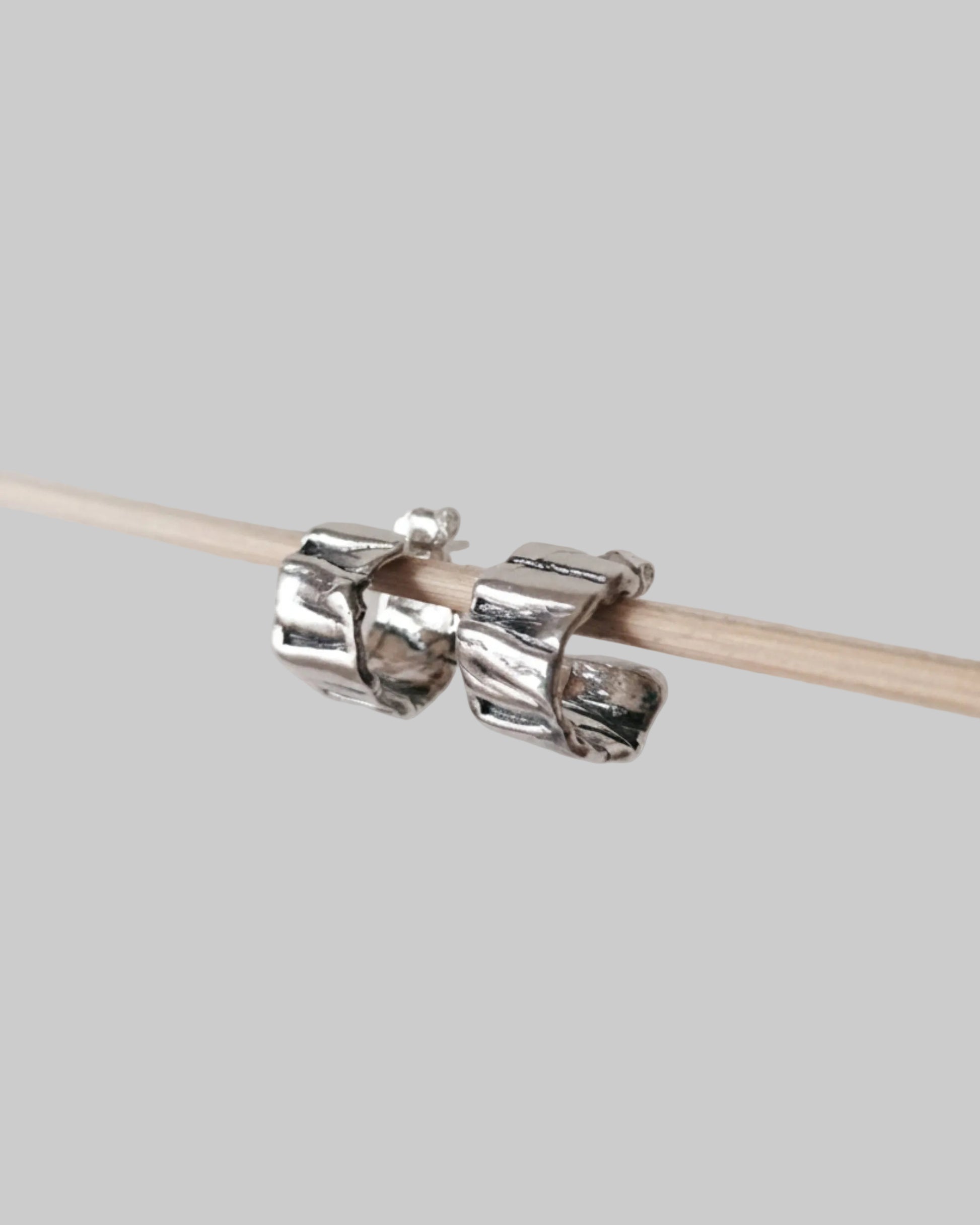 Silver knitting needle holder on a wooden knitting needle against a light gray background