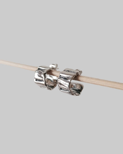 Silver knitting needle holder on a wooden knitting needle against a light gray background