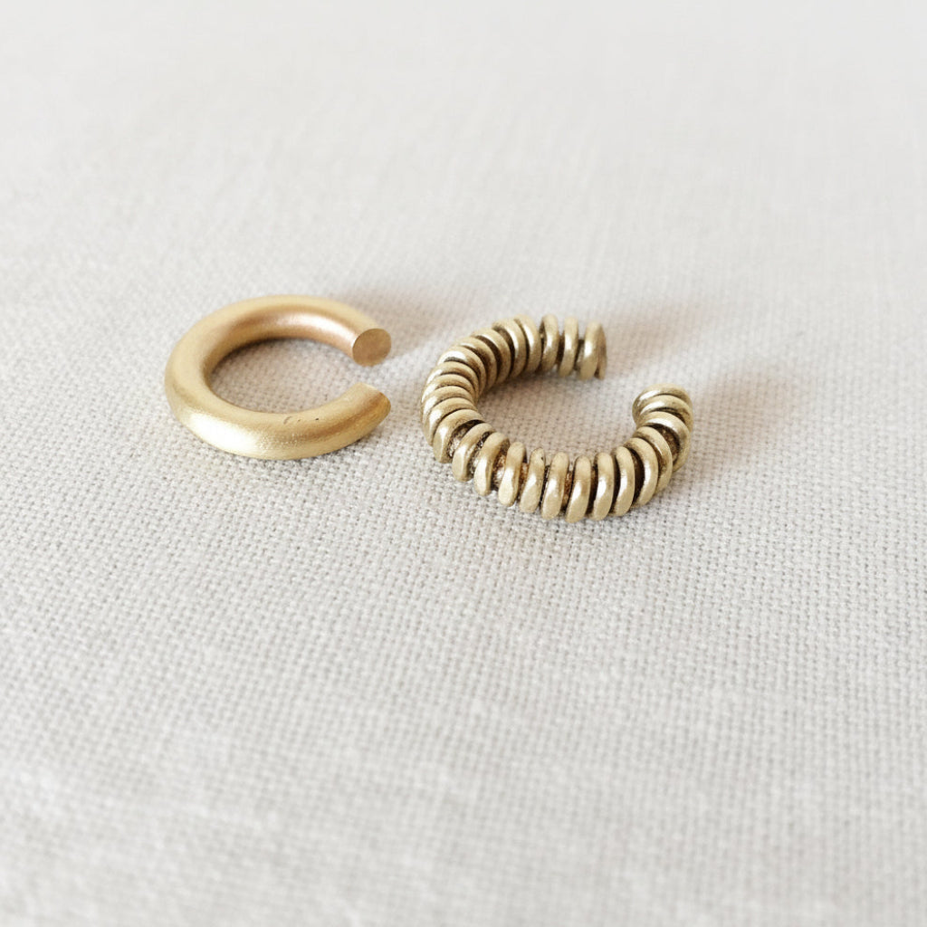 Two gold hoop earrings on a light gray background