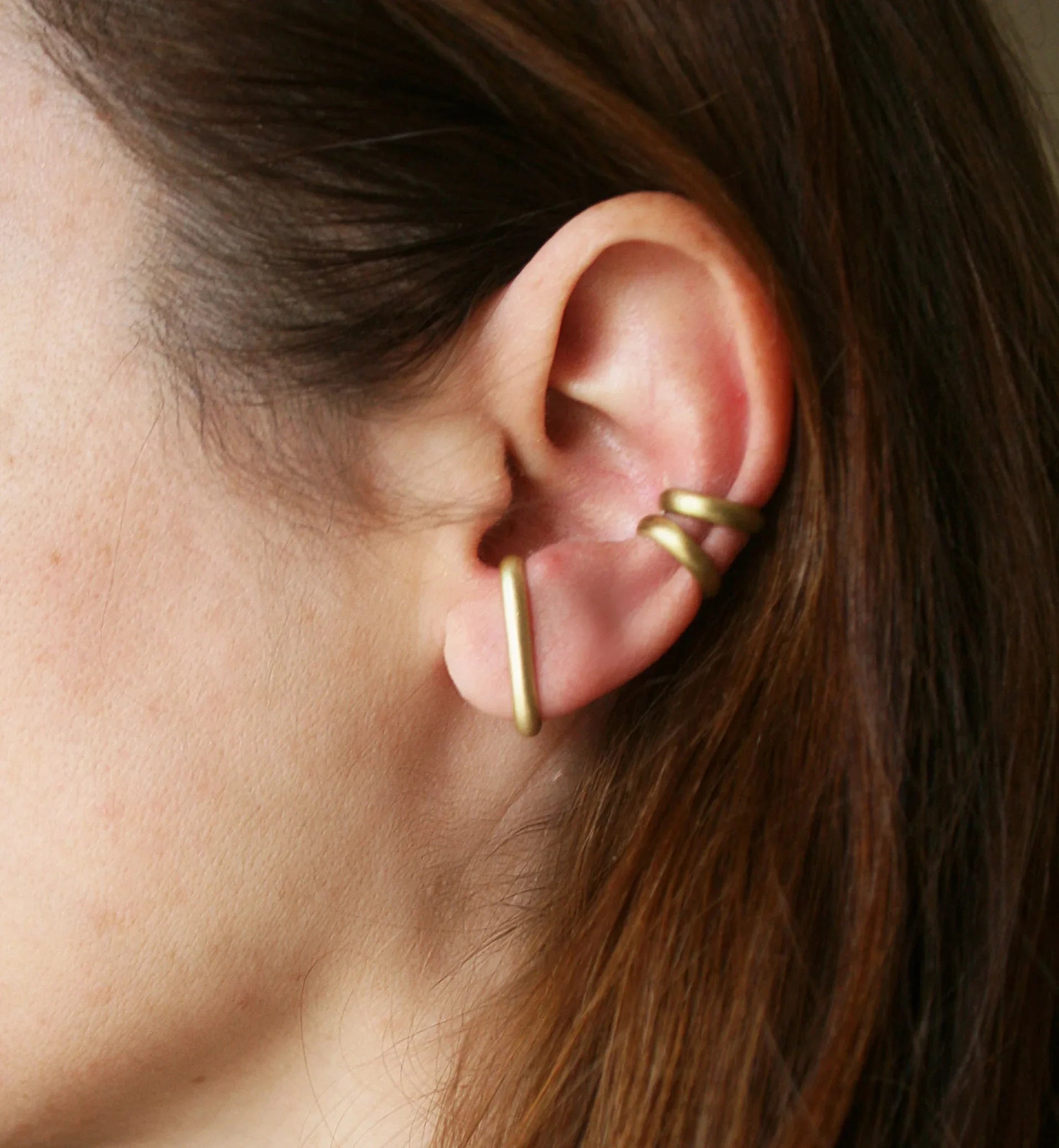 Minimalist gold ear cuff on woman's ear, modern jewelry accessory