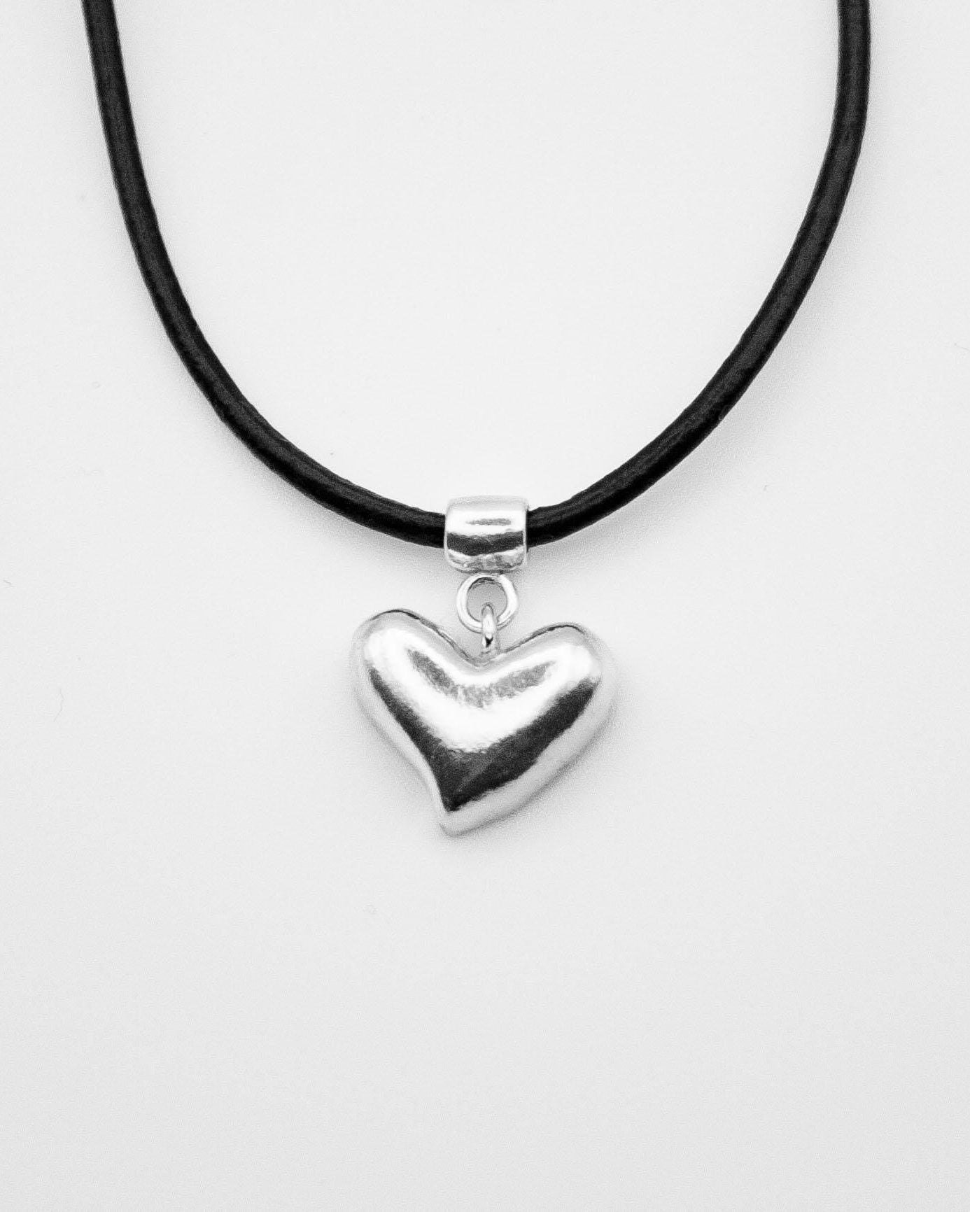 Heart-shaped pendant on a black cord against a white background