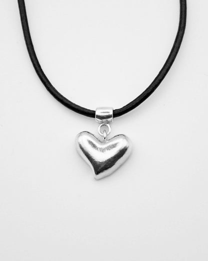 Heart-shaped pendant on a black cord against a white background