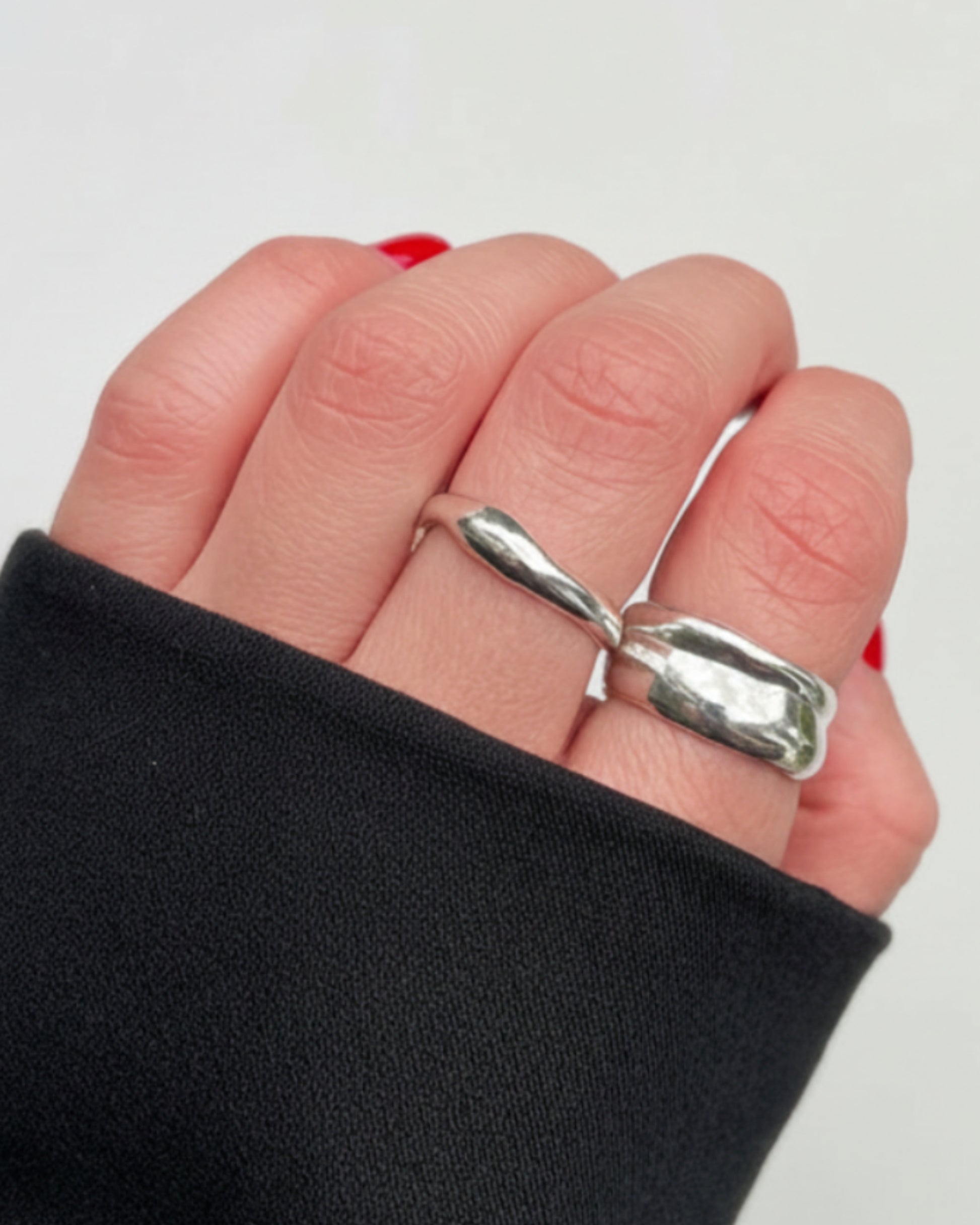 Silver ring on a finger with a plain background