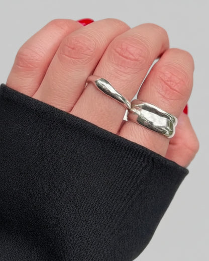 Silver ring on a finger with a plain background