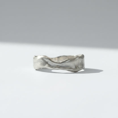 A textured, wavy band ring in a silver-toned metal, photographed against a seamless white background.