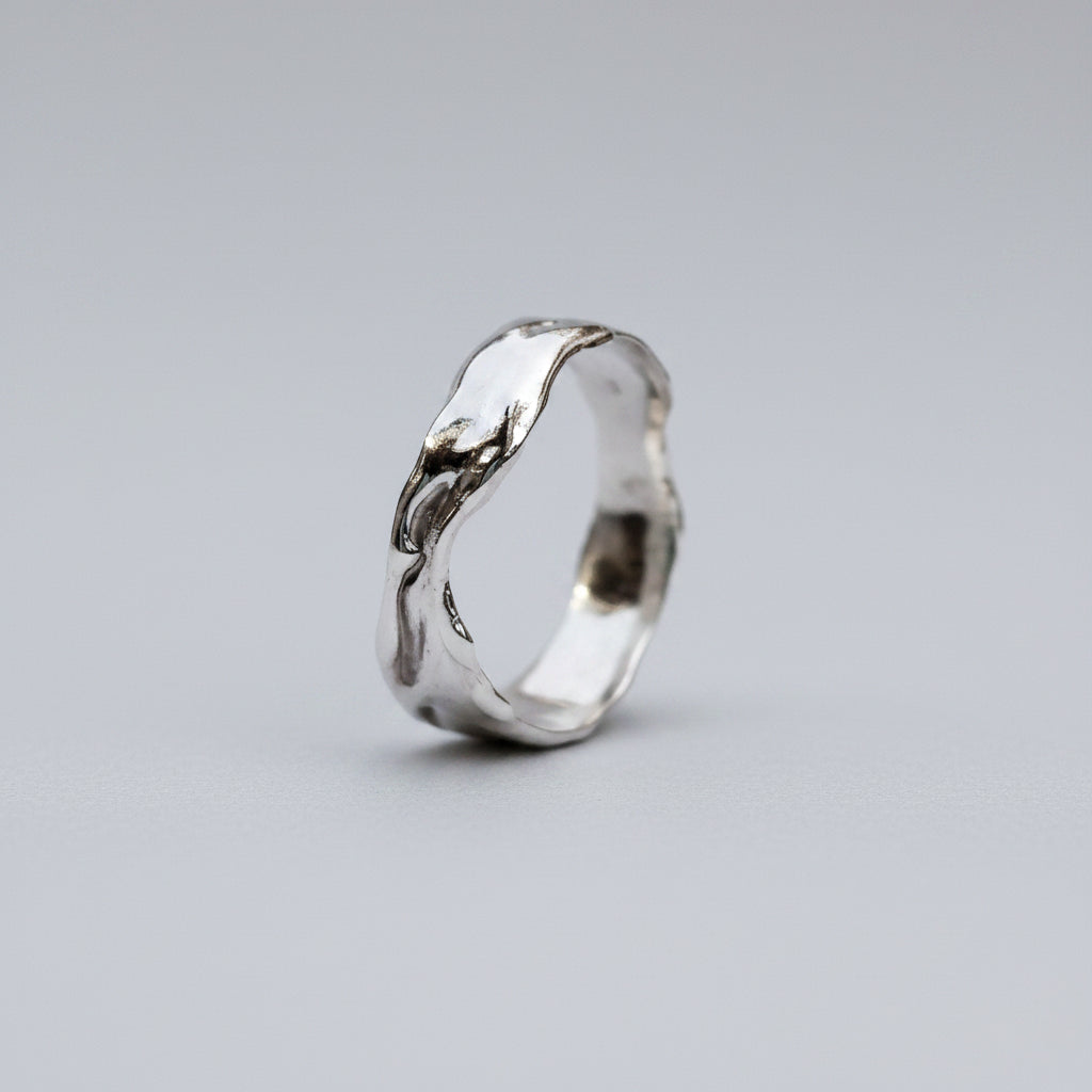 Silver ring with a wavy design on a white background