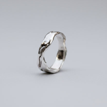 Silver ring with a wavy design on a white background