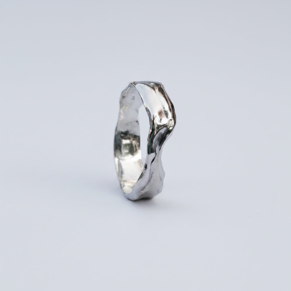 Silver ring with a wavy design on a white background