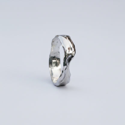 Silver ring with a wavy design on a white background