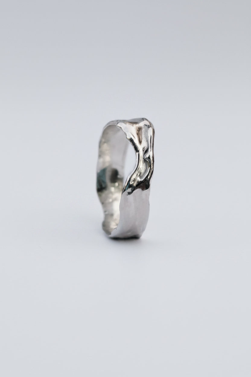 A polished silver ring with a textured, organic wavy design, shown on a plain white background.