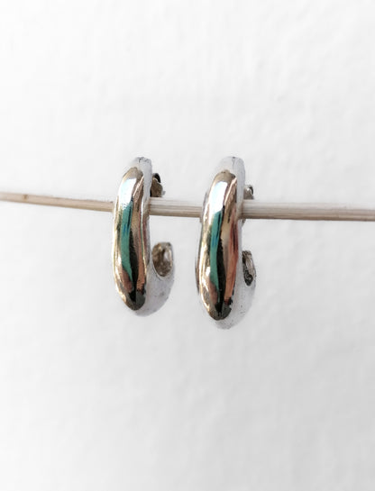 Pair of silver hoop earrings with green accents on a white background