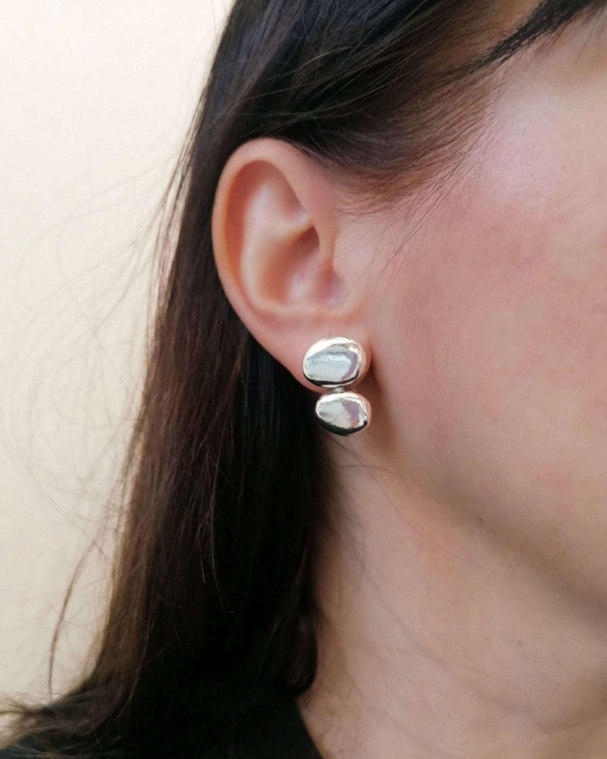 Close-up of an ear wearing a silver earring with a stone.