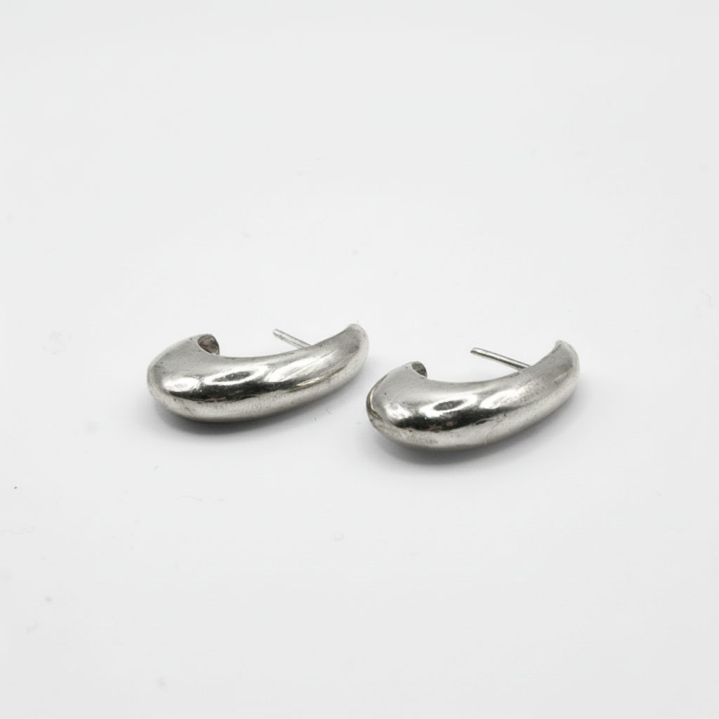 A pair of silver-toned, organic-shaped hoop earrings on a plain white background.