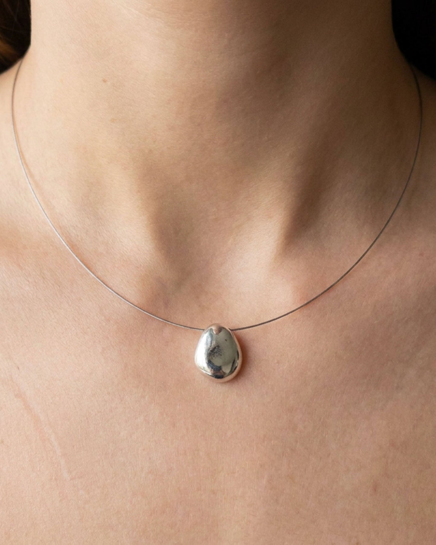 Necklace with a silver pendant on a person's neck