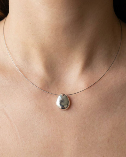 Necklace with a silver pendant on a person's neck