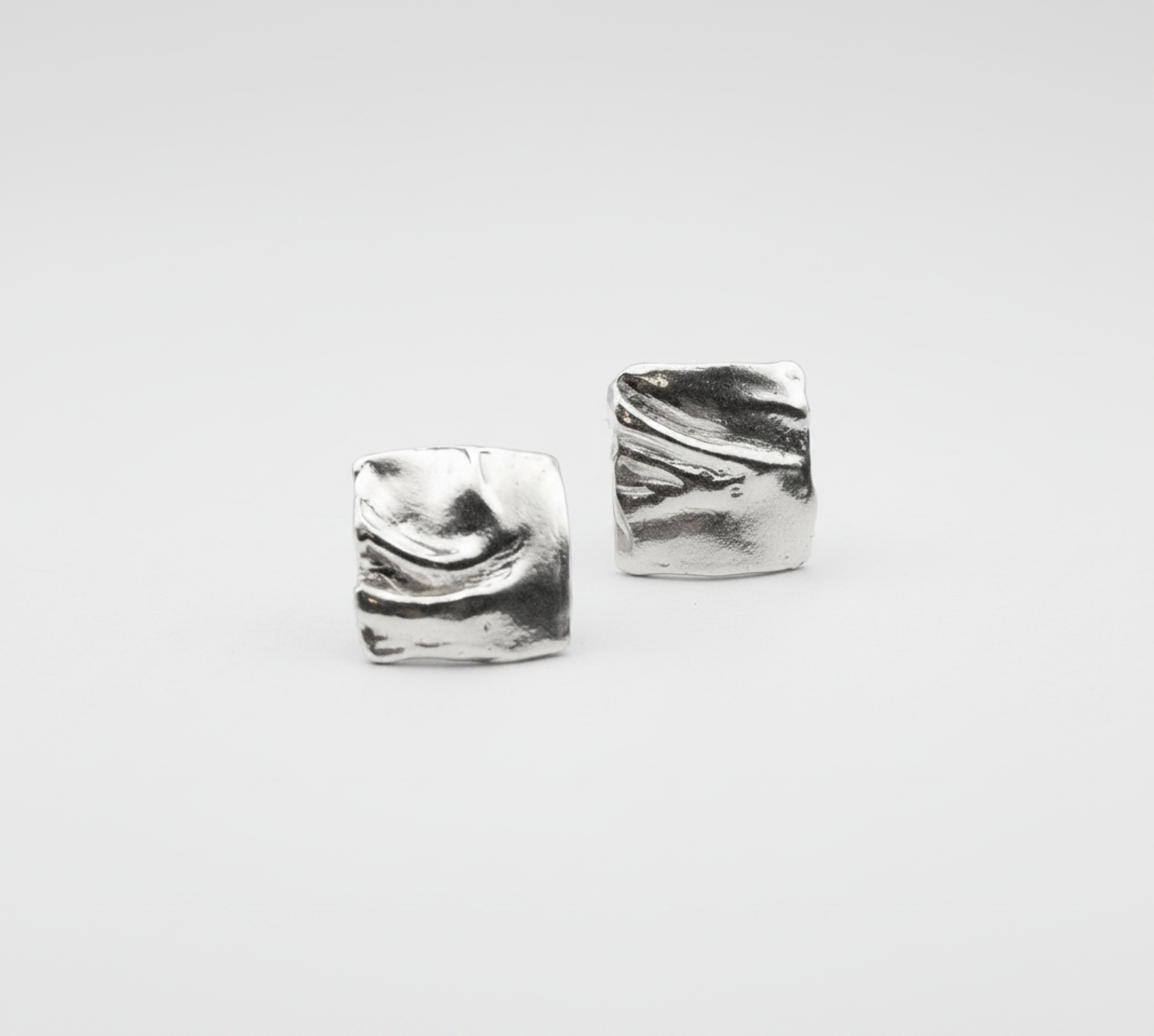 Pair of silver square earrings on a light gray background