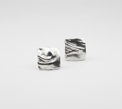 Pair of silver square earrings on a light gray background
