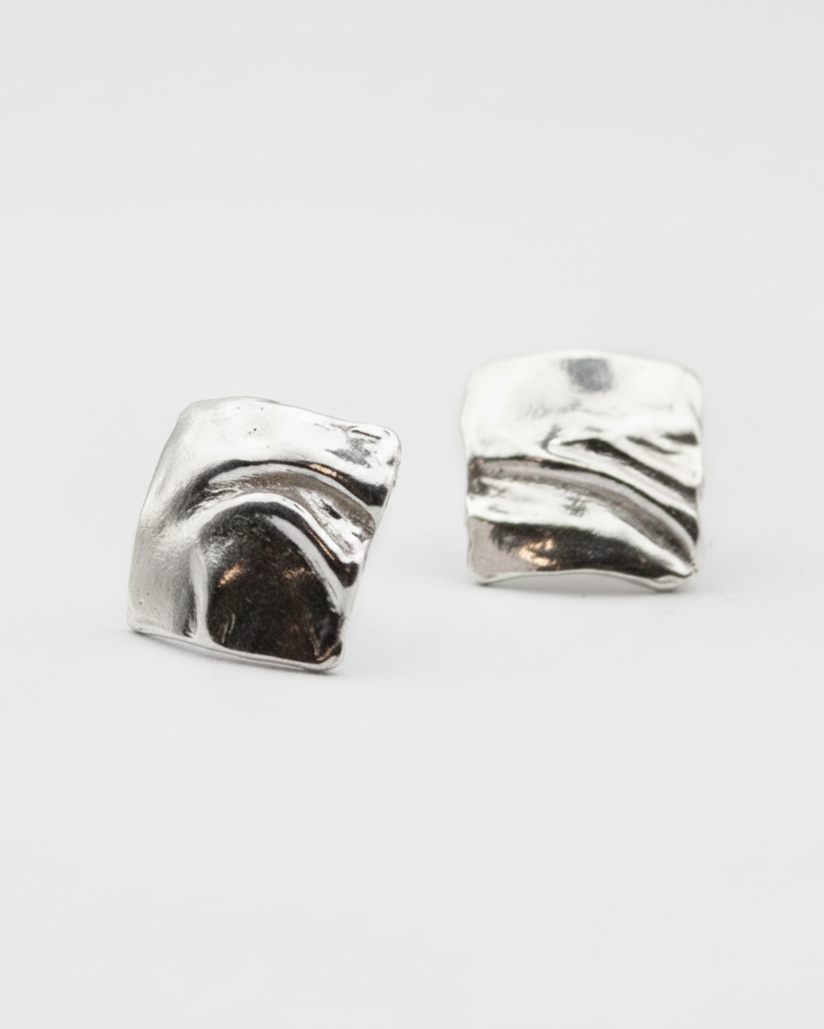 Pair of silver wave-shaped earrings on a light gray background