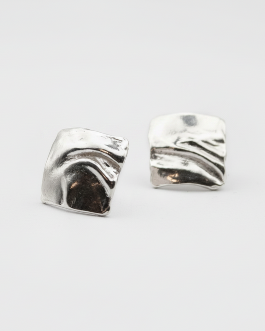 Pair of silver wave-shaped earrings on a light gray background